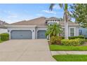 Well-maintained house with a three-car garage, mature trees, and manicured landscaping at 7114 Bowspirit Pl, Apollo Beach, FL 33572