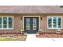 Close-up of the double door entry with modern windows and beautiful landscaping at 7206 Timber Ct, Tampa, FL 33625