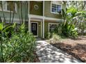 Charming green home with a welcoming front entrance and tropical landscaping at 945 Hamilton Ct, Palm Harbor, FL 34683