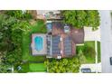 Aerial view of the home featuring a screened pool, solar panels, and putting green at 10053 W Bay St, Seminole, FL 33776