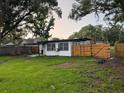 Fenced backyard with a mix of grass, trees, back patio, and wooden fence at 104 W Wildwood St, Tampa, FL 33613
