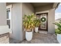 Close-up of a front door with decorative glass, a welcoming wreath, and potted plants at 12451 Nouveau Ave, Spring Hill, FL 34610