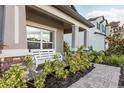 Inviting front porch featuring a white bench, stone accents, and beautiful landscaping at 12451 Nouveau Ave, Spring Hill, FL 34610
