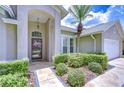 Welcoming home with lush landscaping, including a mature palm, and a decorative front door with glass window at 13602 Fawn Ridge Blvd, Tampa, FL 33626