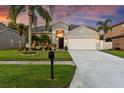 Inviting single-story home featuring a lush lawn, tropical landscaping, a two-car garage, and a paved walkway at 1631 Shady Oaks Dr, Oldsmar, FL 34677