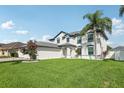 Beautiful two-story home with a well-manicured lawn, flowering trees, and a three car garage at 1802 Regal Mist Loop, Trinity, FL 34655