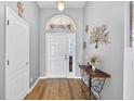 Inviting foyer with wood-look flooring, decorative console table, and a view of the bright front door at 2527 Butterfly Landing Dr, Land O Lakes, FL 34638