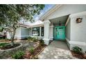 Welcoming entrance with a covered porch, stylish blue door, and tasteful landscaping at 2609 Sunnyside Cir, Palm Harbor, FL 34684
