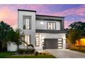 Contemporary two-story home with dark accents, sleek garage door, and a beautifully landscaped front yard at 2707 Ridgewood Ave, Tampa, FL 33602