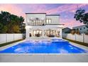 Stunning backyard showcasing a large, illuminated pool and spa with a covered patio and second story balcony at 2707 Ridgewood Ave, Tampa, FL 33602