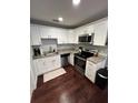 Well-lit kitchen featuring white cabinets, stainless steel appliances, granite countertops, and dark hardwood flooring at 302 W Fern St, Tampa, FL 33604