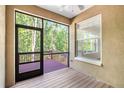 Screened-in patio with wood flooring, a fan, and a view of lush trees at 4920 Anniston Cir, Tampa, FL 33647