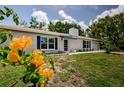 View of the home's white brick exterior, complemented by blue shutters and vibrant flowers at 7332 Janczlik Dr, New Port Richey, FL 34652