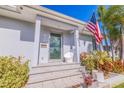 Inviting front entrance of the home featuring a glass door, flag, and well-manicured landscaping at 827 Placido Ne Way, St Petersburg, FL 33704