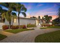 Charming single-story house with tropical landscaping and a brick paved walkway at sunset at 827 Placido Ne Way, St Petersburg, FL 33704