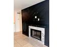 Living room featuring a black accent wall and a cozy fireplace with marble tile surround at 9481 Highland Oak Dr # 1101, Tampa, FL 33647