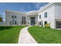 Elegant home featuring a lush green lawn, a curved walkway, and a grand entrance with modern architectural details at 11313 Knights Griffin Rd, Thonotosassa, FL 33592