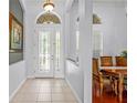 Bright foyer with tiled floor, arched doorway and decorative glass door leading to the dining room at 12801 Stanwyck Cir, Tampa, FL 33626