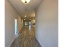 A long hallway with wood-look tile flooring leads to the open-concept living area and kitchen at 13374 Ogden Glade Rd, Dade City, FL 33525