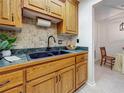 Classic kitchen with wood cabinets, black sink, and a decorative tile backsplash at 2442 Enterprise Rd # 6, Clearwater, FL 33763