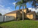 Beautiful home exterior with well-maintained lawn, palm tree, stone accents, and white fence at 31141 Harthorn Ct, Wesley Chapel, FL 33543