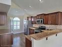 Modern kitchen featuring stainless steel appliances, dark cabinets, granite countertops, and recessed lighting at 31141 Harthorn Ct, Wesley Chapel, FL 33543