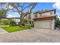 Beautiful two-story home with a red tile roof and a lush green front yard with a large shade tree at 3307 W Knights Ave, Tampa, FL 33611