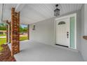 Welcoming covered porch with brick columns, painted concrete and updated front door with decorative window at 4313 Riviera Ct, Spring Hill, FL 34608