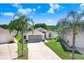 Single-story home with well-manicured lawn and mature palm trees is situated next to a picturesque lake at 4407 Whitton Way, New Port Richey, FL 34653
