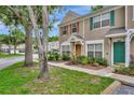 Well-maintained townhome with stucco exterior, decorative shutters, and a lush front garden landscape at 5502 Carrollwood Key Dr, Tampa, FL 33624