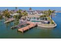 Waterfront property with dock, boat lift, pool, lush landscaping, and outdoor entertaining area at 5950 Bikini N Way, St Pete Beach, FL 33706
