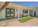 Inviting covered porch with white columns, double doors, and brick walkway, perfect for relaxing at 5950 Bikini N Way, St Pete Beach, FL 33706