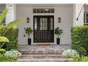 Elegant front entrance with a stylish black door, potted plants, and stone steps at 10003 Brompton Dr, Tampa, FL 33626