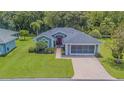 Charming single-story home with well-manicured lawn, brick driveway, and a screened-in two car garage at 10728 Moshie Ln, San Antonio, FL 33576