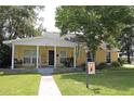 Inviting yellow home featuring a covered front porch, well-manicured lawn, and mature trees at 13637 13Th St, Dade City, FL 33525