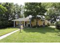 Welcoming yellow home with lush green lawn, mature shade trees, and a charming covered front porch at 13637 13Th St, Dade City, FL 33525