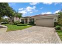 Beautiful home showcasing a manicured lawn, vibrant landscaping, and a spacious paver driveway leading to the garage at 19409 Wingrove Ln, Lutz, FL 33558