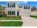 Charming two-story home with blue shutters, white walls, a two-car garage, and well manicured landscaping at 33657 Field Maple Loop, Wesley Chapel, FL 33545