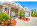Inviting home entrance with double front doors, mature plants, mulch, and an American flag at 4495 Secretariat Run, Spring Hill, FL 34609