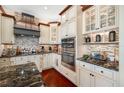 Stylish kitchen with custom cabinetry, stone backsplash, stainless steel appliances, and hardwood floors at 4495 Secretariat Run, Spring Hill, FL 34609