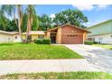 Exterior view of a home with stone accents, lush landscaping, and a spacious driveway at 4709 Heath Ave, Tampa, FL 33624