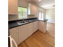 Bright kitchen features white cabinets, black countertops and wood laminate flooring at 5644 Samter Ct, Tampa, FL 33611