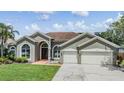 Charming single-story home with a well-manicured lawn, lush landscaping, and a two-car garage at 9126 Cypress Keep Ln, Odessa, FL 33556