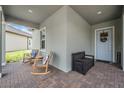 Inviting front porch area with rocking chairs and a bench, perfect for relaxing and enjoying the outdoors at 10278 Otter Sky Ct, San Antonio, FL 33576