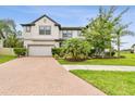Attractive two-story home with a brick driveway, green lawn, and mature trees at 10701 Morning Dew Way, Tampa, FL 33647