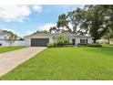 Beautiful home with a lush green lawn, mature trees, and attached garage at 1513 Loretta Ct, Brandon, FL 33511