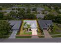 An aerial view of a well-maintained home showcasing its landscaped yard, mature trees, and proximity to a serene lake at 18549 Grand Club Dr, Hudson, FL 34667
