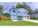 Charming two-story blue home with a second story balcony and a well-manicured front lawn at 309 Congress St, Oldsmar, FL 34677
