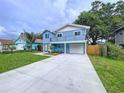 Inviting two-story home featuring an attached garage, a well-manicured lawn and a long driveway at 309 Congress St, Oldsmar, FL 34677