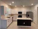 Bright kitchen features white cabinetry, stainless steel appliances, and a center island with dark base at 36233 Joseph Blake St, Zephyrhills, FL 33541